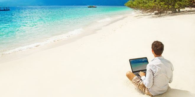 man with laptop on colorful beach of island